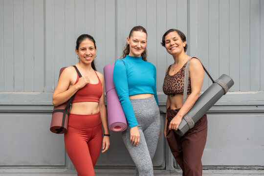Multiethnic women with yoga mat smiling after fitness class