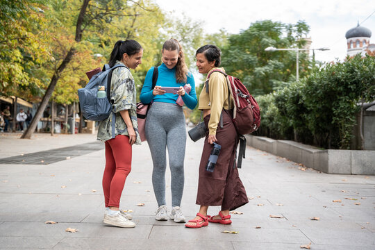 Multiethnic women checking phone before street yoga class