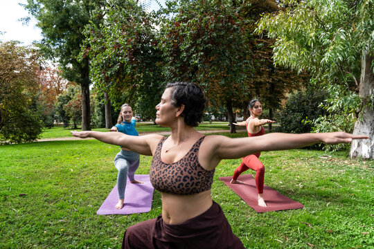Multiethnic women doing yoga warrior pose in a park