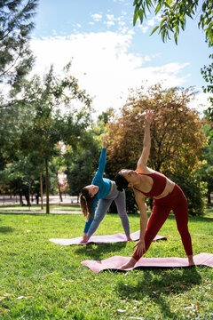 Multiethnic women doing outdoor yoga in a sunny park