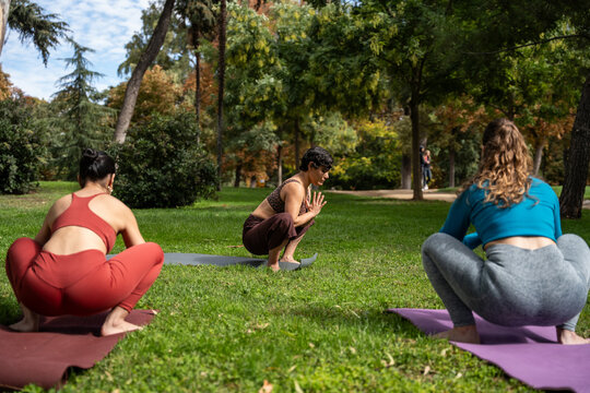 Multiethnic women practicing yoga squats in a city park