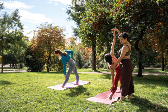 Multiethnic women practicing yoga with instructor in park