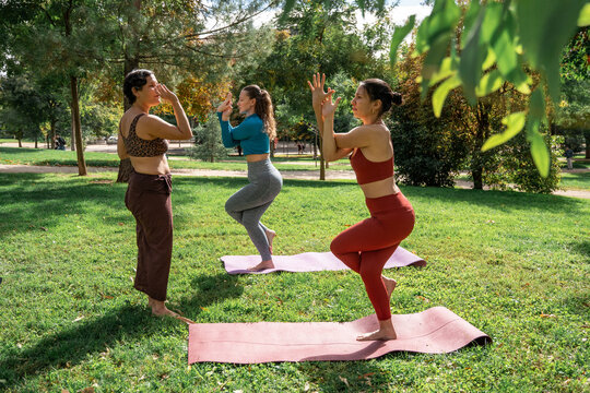 Multiethnic women practicing yoga balance pose in park