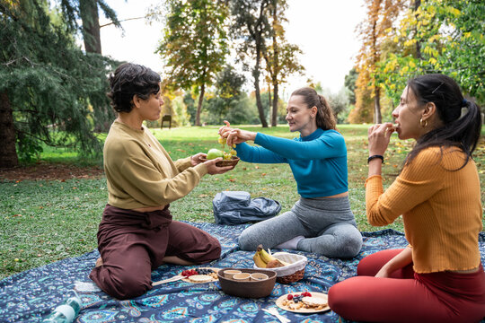 Multiethnic women share snack during picnic in park