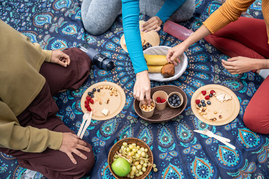 Multiethnic women sharing healthy picnic snacks on blanket