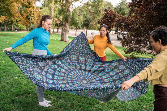 Outdoor spiritual retreat group spreading patterned blanket