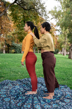 Outdoor yoga adjustment session at spiritual retreat in park