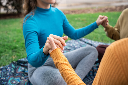 Group meditation circle holding hands on outdoor retreat