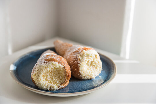 Conic cannoli with ricotta cream on blue plate, close-up