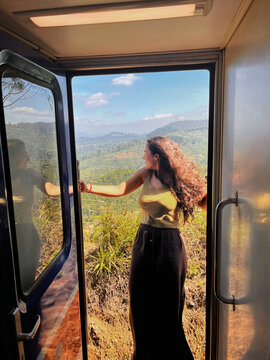 Young woman enjoying scenic view from train in Sri Lanka