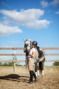 Woman embracing horse in equestrian setting