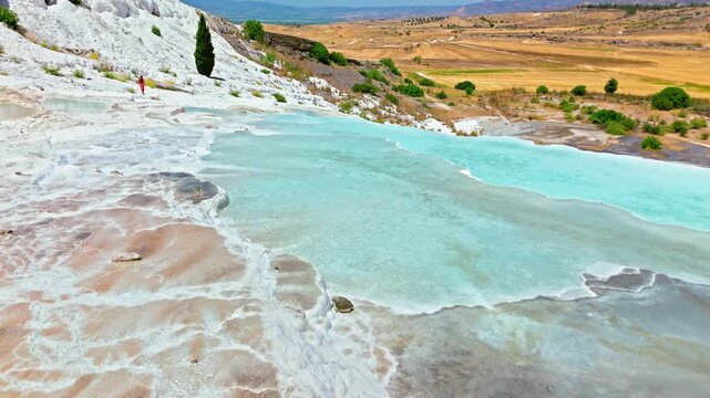 Drone view of Travertines of Pamukkale, Turkey. Shallow turquoise thermal pools and white limestone slopes create a scenic landmark view.
