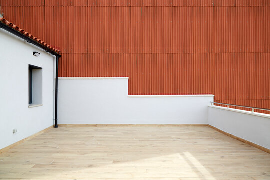 Modern empty rooftop terrace with wood floor and red wall