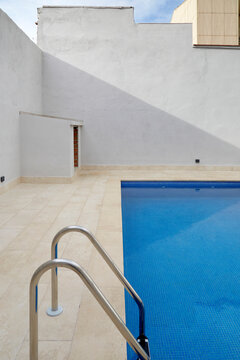 Modern courtyard pool beside minimalist white exterior wall