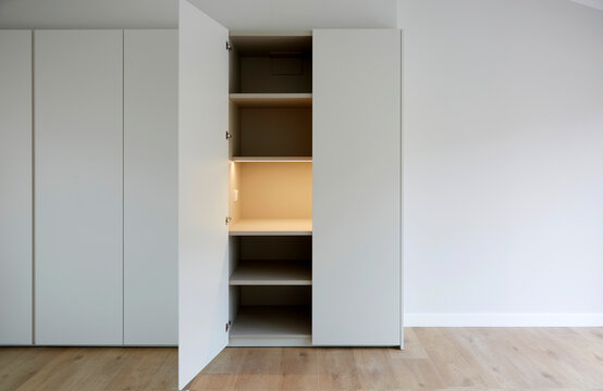 Minimal white built in wardrobe with open door and shelf
