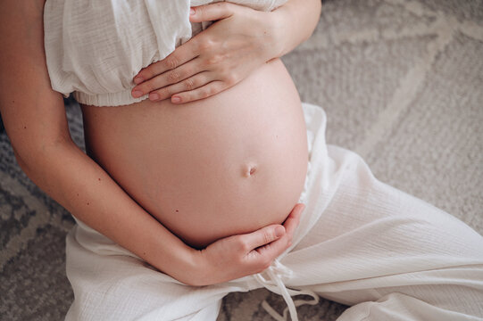 Pregnant woman embracing her belly in morning light