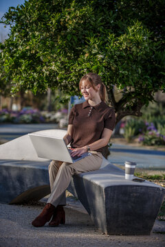 Woman working on laptop in a serene park environment