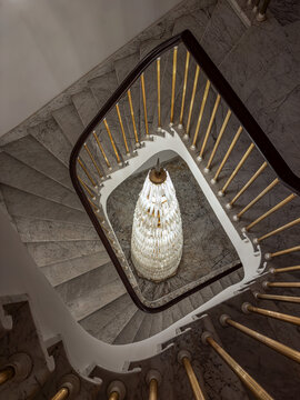Overhead of elegant marble spiral staircase with crystal chandelier