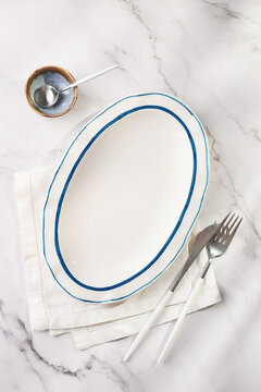 Minimal table setting with oval plate on marble surface