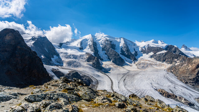 The stunning Piz Palu towers over the vast expanse of Pers Glacier, showcasing the beauty of the Bernina Range in the Swiss Alps. This alpine landscape captures the essence of high mountain adventure.