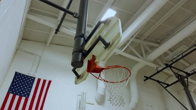 Backboard inside an indoor gymnasium with bright lights and high ceiling. 