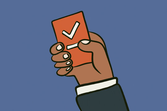 Black hand holding ballot card with check mark for voting