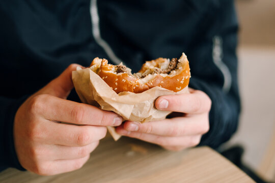 Person holding a half eaten cheeseburger wrapped in paper
