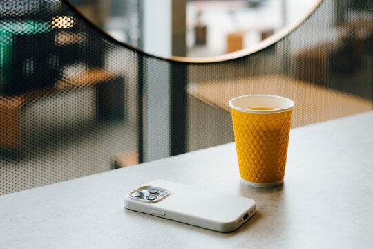 Minimal cafe table with smartphone and coffee cup by window