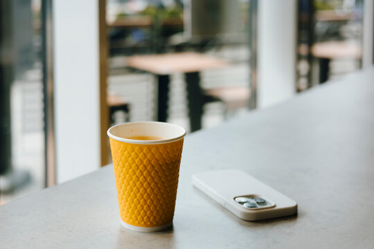 Coffee cup and smartphone on table in modern cafe interior