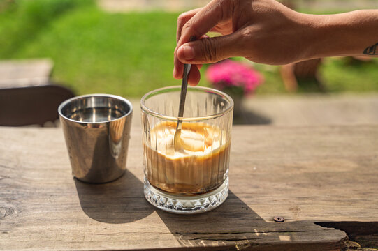 Creamy egg coffee being stirred in a glass cup