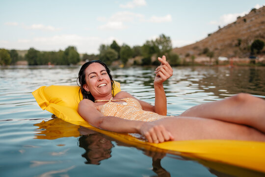 Woman relaxing on inflatable float on lake in summer sun