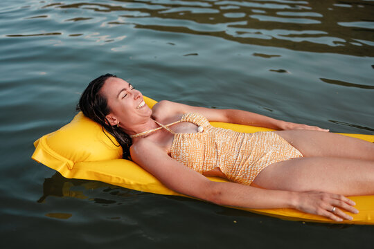 Woman relaxing on inflatable float at lake in summer sun