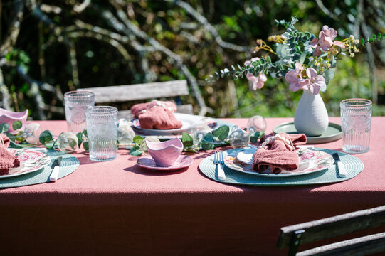 Spring outdoor table setting with pink linen and floral decor