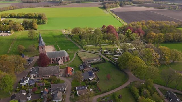 Drone flying over a small village with a church and surrounding fields