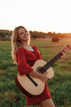 Young blonde enjoying music in a field at sunset