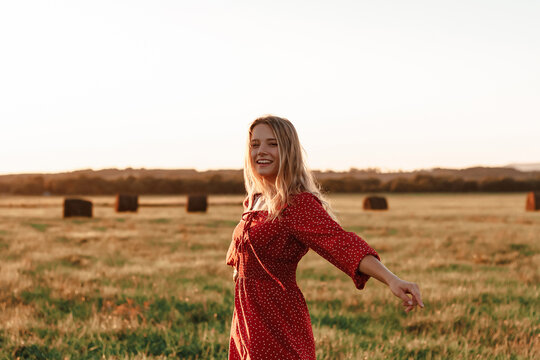 Woman in red dress waving in grassy field