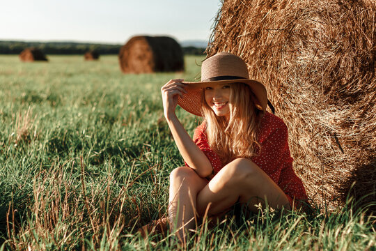 Young woman enjoying summer near haystack at sunset