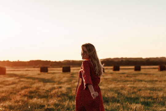 Young blonde woman in red dress running at sunset