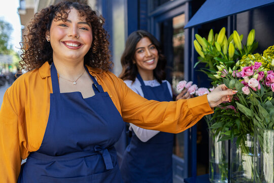 Florist women in blue aprons arranging vibrant bouquets