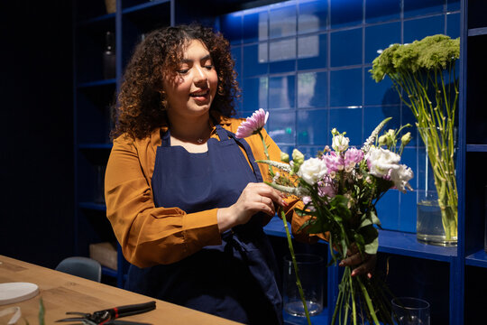 Florist arranging bouquet in blue flower shop