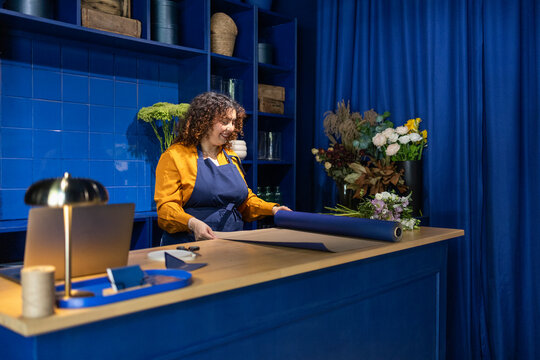 Florist in a blue-themed flower shop with vibrant bouquet