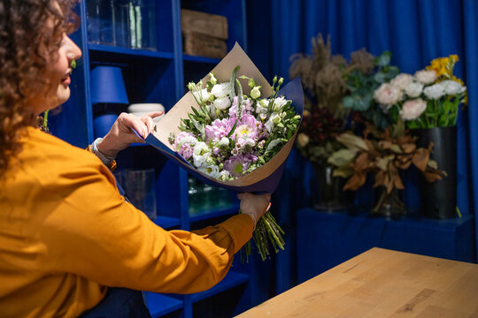 Florist displaying elegant bouquet in blue flower shop