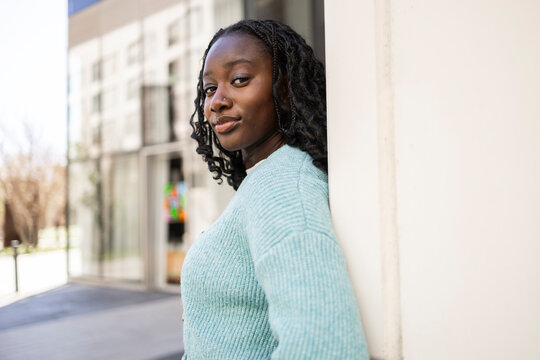 Young African woman leaning on wall in modern city street