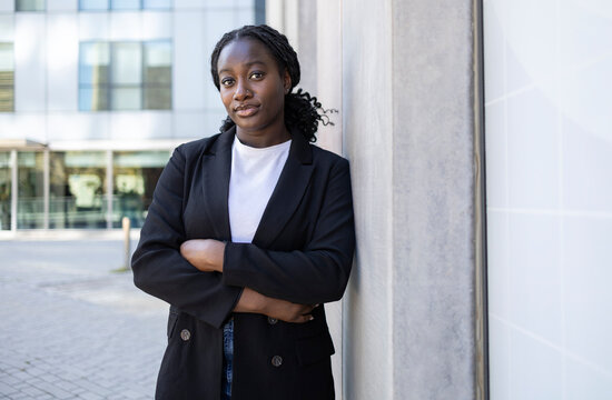 Confident African businesswoman standing by modern office building