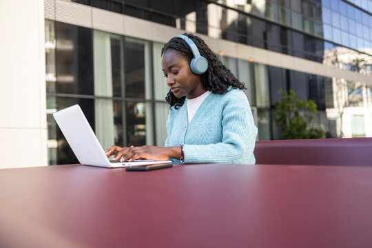 African woman working on laptop outdoors with headphone