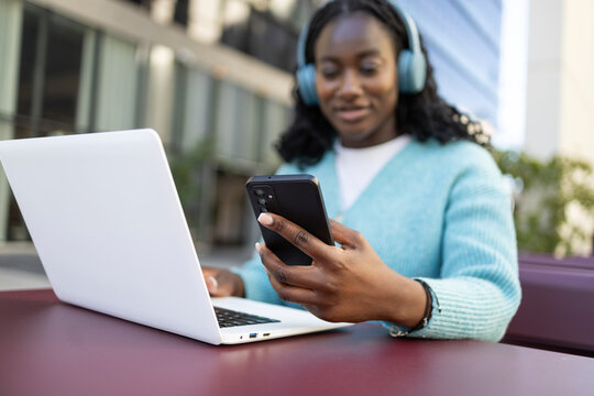 African woman using laptop and smartphone outdoors