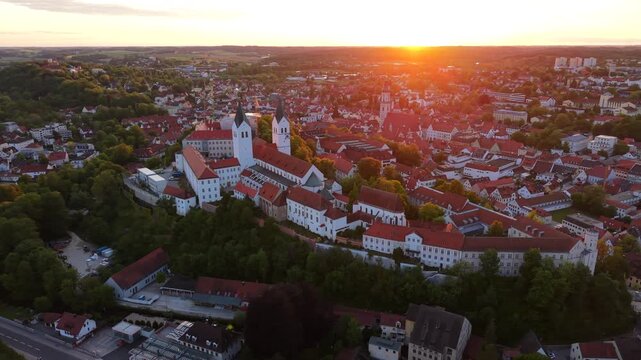 Freising old town and the Domberg rise in a drone aerial view across Bavaria, Germany, with Freising Cathedral, St. George Church, and the Residenzturm glowing in warm evening light.