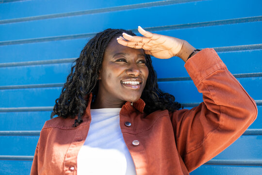 Smiling African woman shading eyes in bright sunlight outdoors