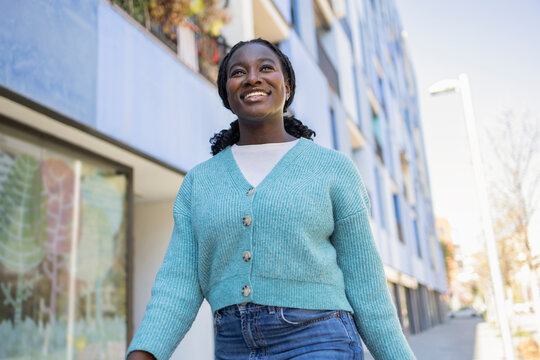 Smiling African woman walking in city on sunny day