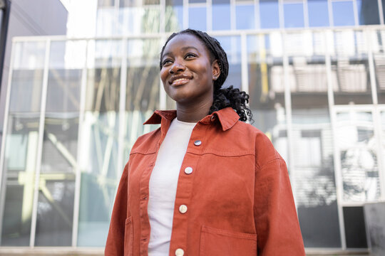 Smiling African woman outdoors by modern glass building